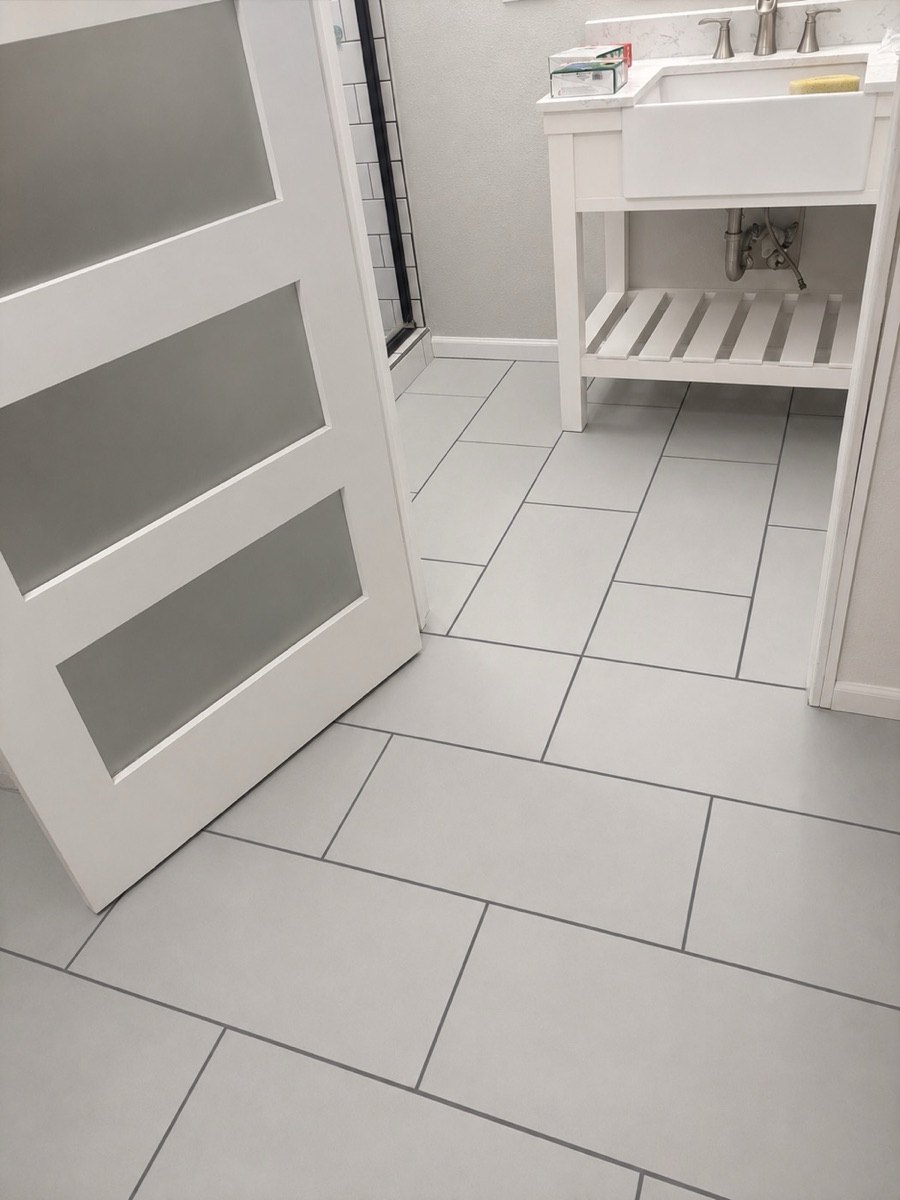 Finished bathroom with new gray tile floor and white vanity